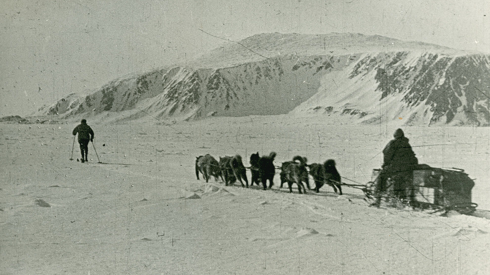 Hundespann med slede og en person som går foran og en person på sleden