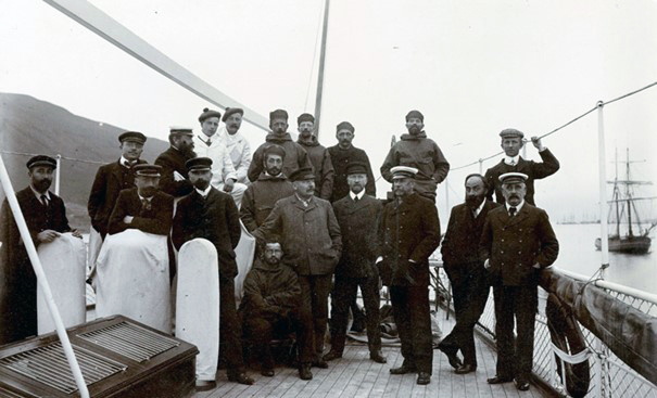 Gruppebilde av 20 menn på et båtdekk, de er kledd i uniformer og ullklær.