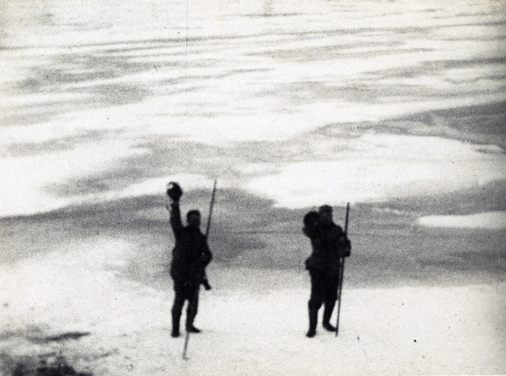 To menn står på isen og vinker