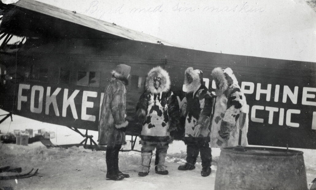Fire menn i polarpels står foran et fokkerfly