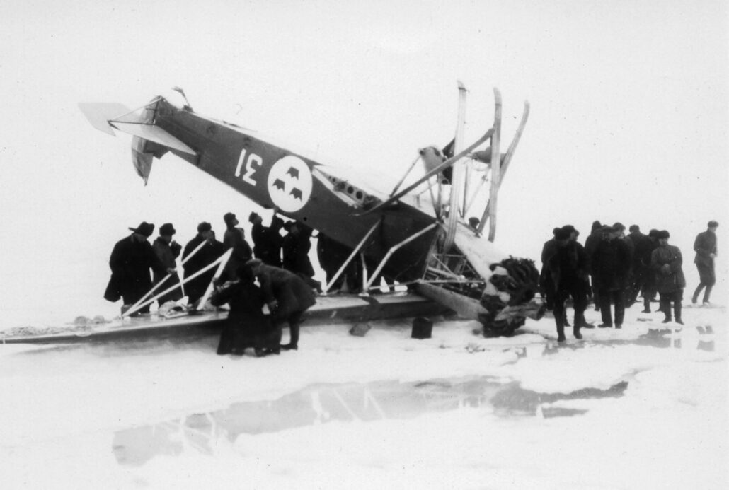 Folkemengde på isen står rundt et veltet sjøfly.