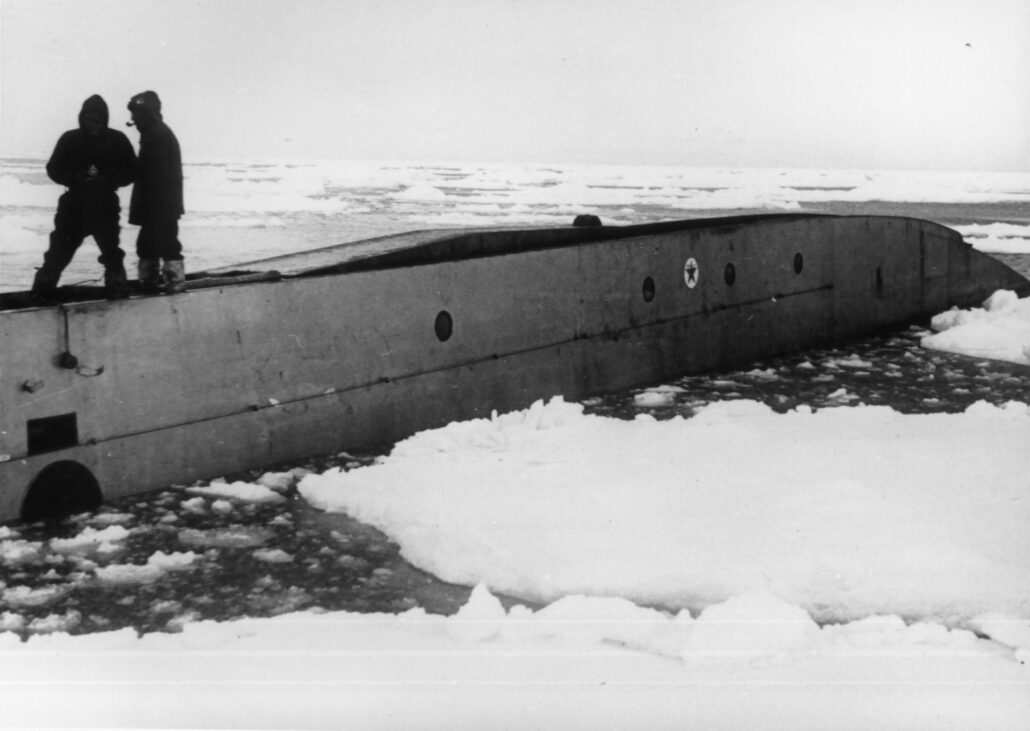 To menn står oppå en ubåt i isråk.Texaco-logo synlig på skroget.