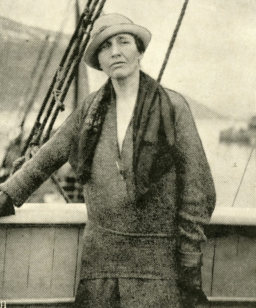 Kvinne ombord på båt med hatt og kåpe
