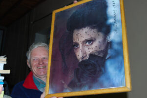 Mann smiler og holder frem et portrett av en kvinne.