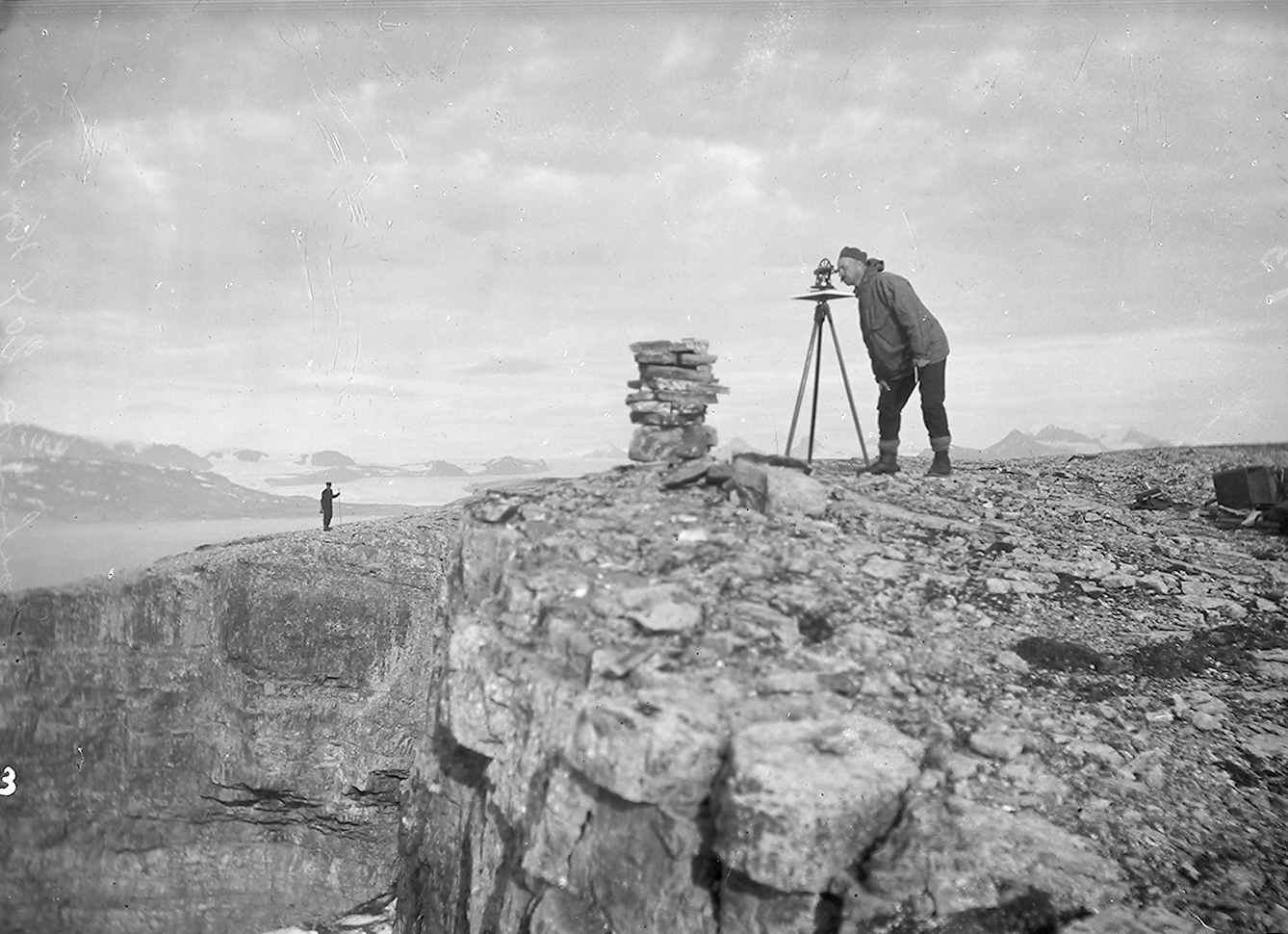 Mann med anorakk ser gjennom et måleinstrument på en fjellpynt