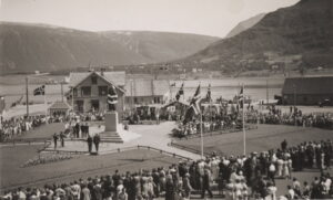 Folkemenge på et torg med en statue som blir avduket. Norske flagg vaier på en flaggstang