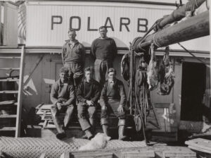 Fem menn poserer på båtdekk foran navnet Polarbjørn