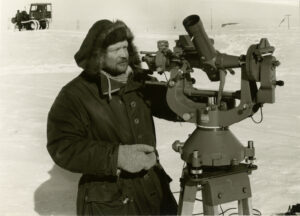 Mann i anorakk og hette gjør observasjoner i apparat som står ute på snø