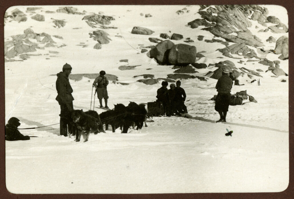 Hundespann og seks personer ved foten av et fjell