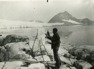 Mann maler bilde i fjære, isbre i bakgrunnen