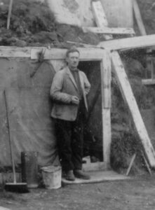 Mann lener seg inntil en enkel hytte