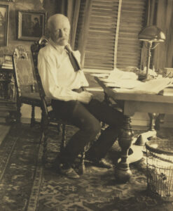 Mann med hvit skjort eog slips sitter ved et skrivebord