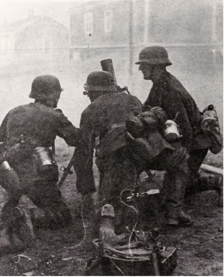 Tre soldater med våpen sitter på huk, det er mye røyk rundt dem