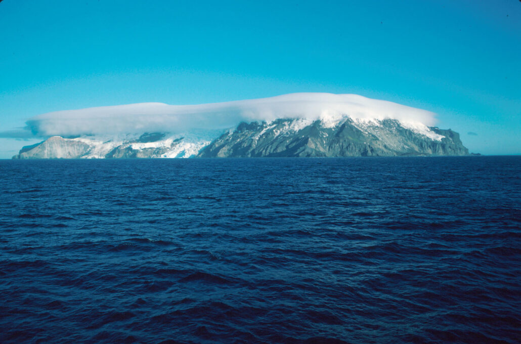 landskapsbilde som viser øya med mørk blå hav og blå himmel.