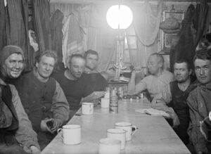 Gruppebilde med menn som sitter ved et langbord i en båt