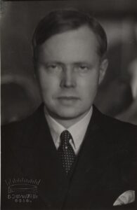 Portrett av mann med mørk dress og prikkete slips